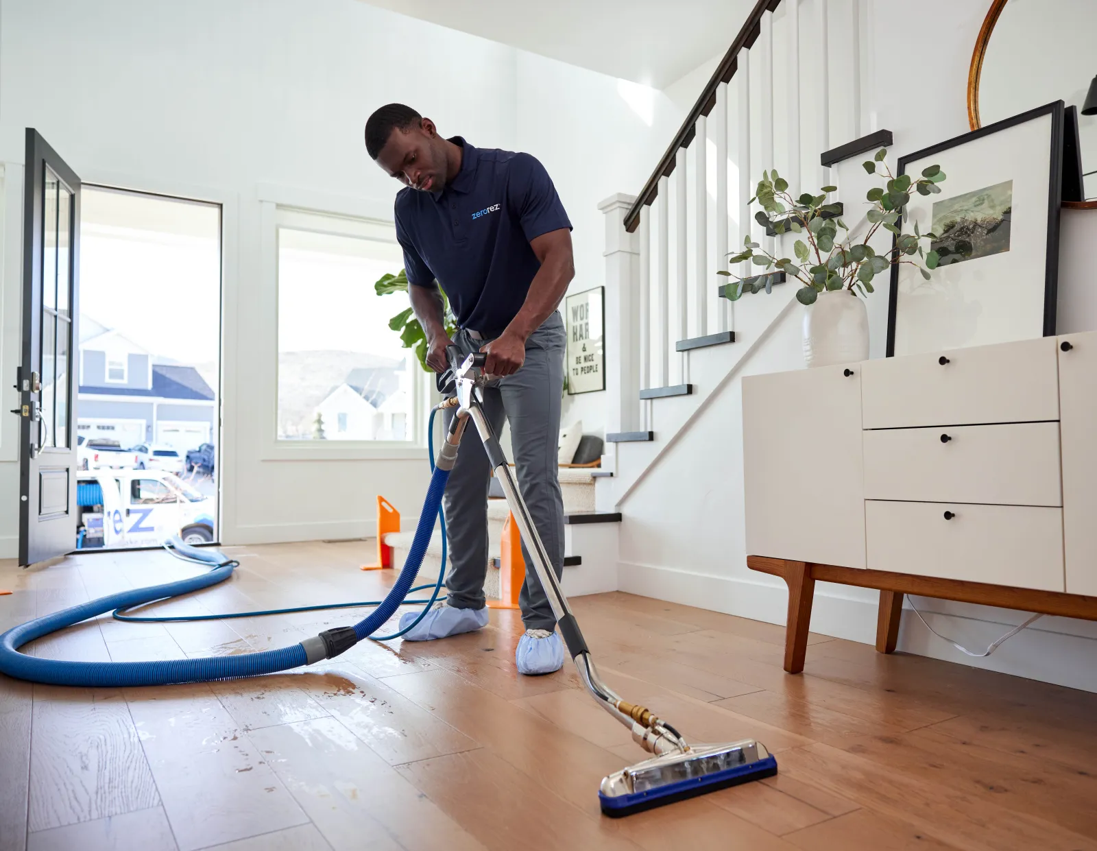 male black Zerorez® technician professional cleaning hardwood floors in a home with the Zr® Wand