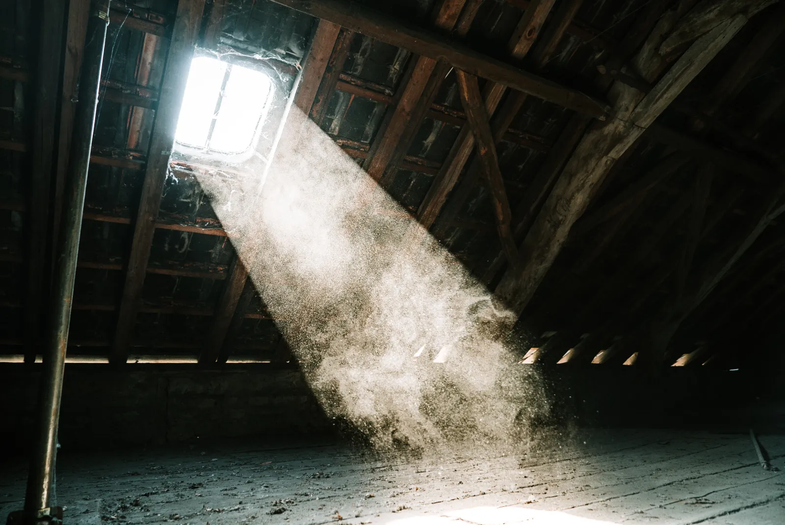 light shining in through an abandoned empty house skylight showcasing tiny dust particles in the air