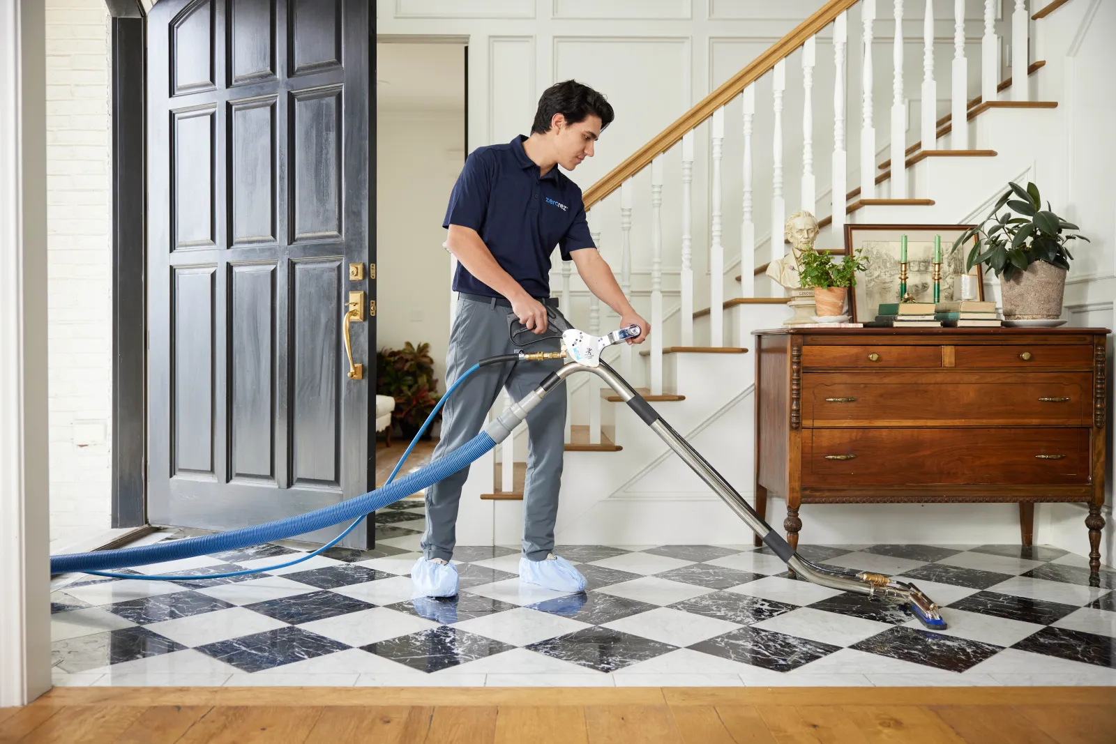 male Zerorez technician cleaning a black and white checkered tile floor in a home entryway