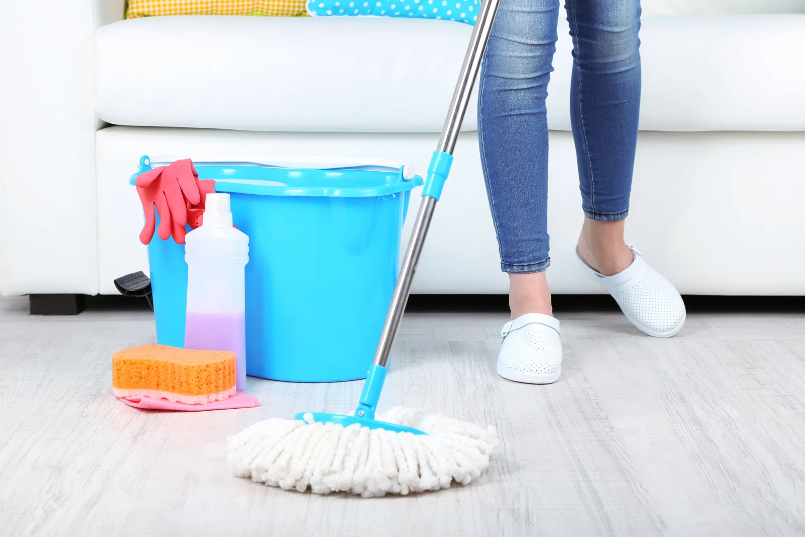 close up of mop cleaning the floor after it was vacuumed with a cleaning mop bucket beside her feet