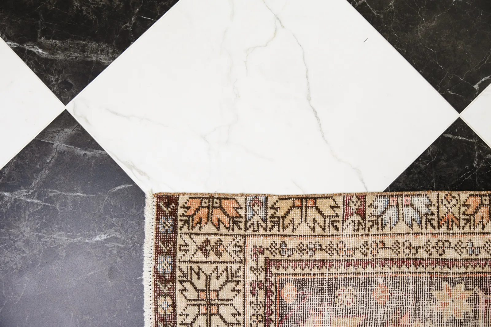 overhead shot of a black and white tile floor with a brown carpet runner rug in the bottom right corner which helps tile not be slippery