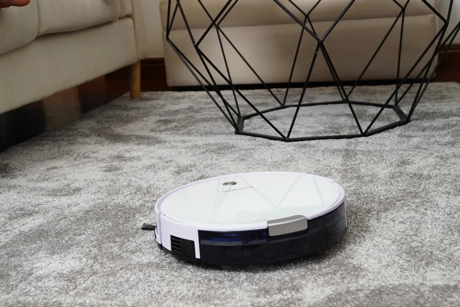 white robot vacuum being loud as it cleans a carpeted living area
