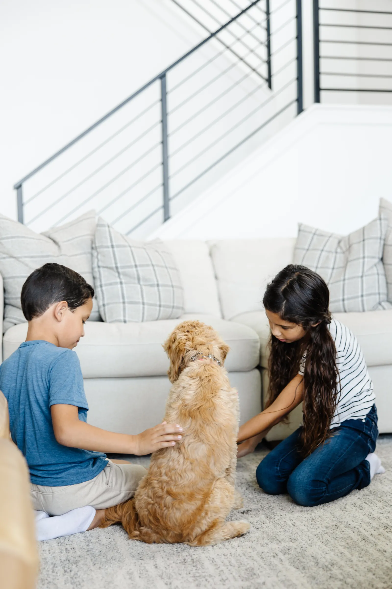 two kids on a rug playing with a dog