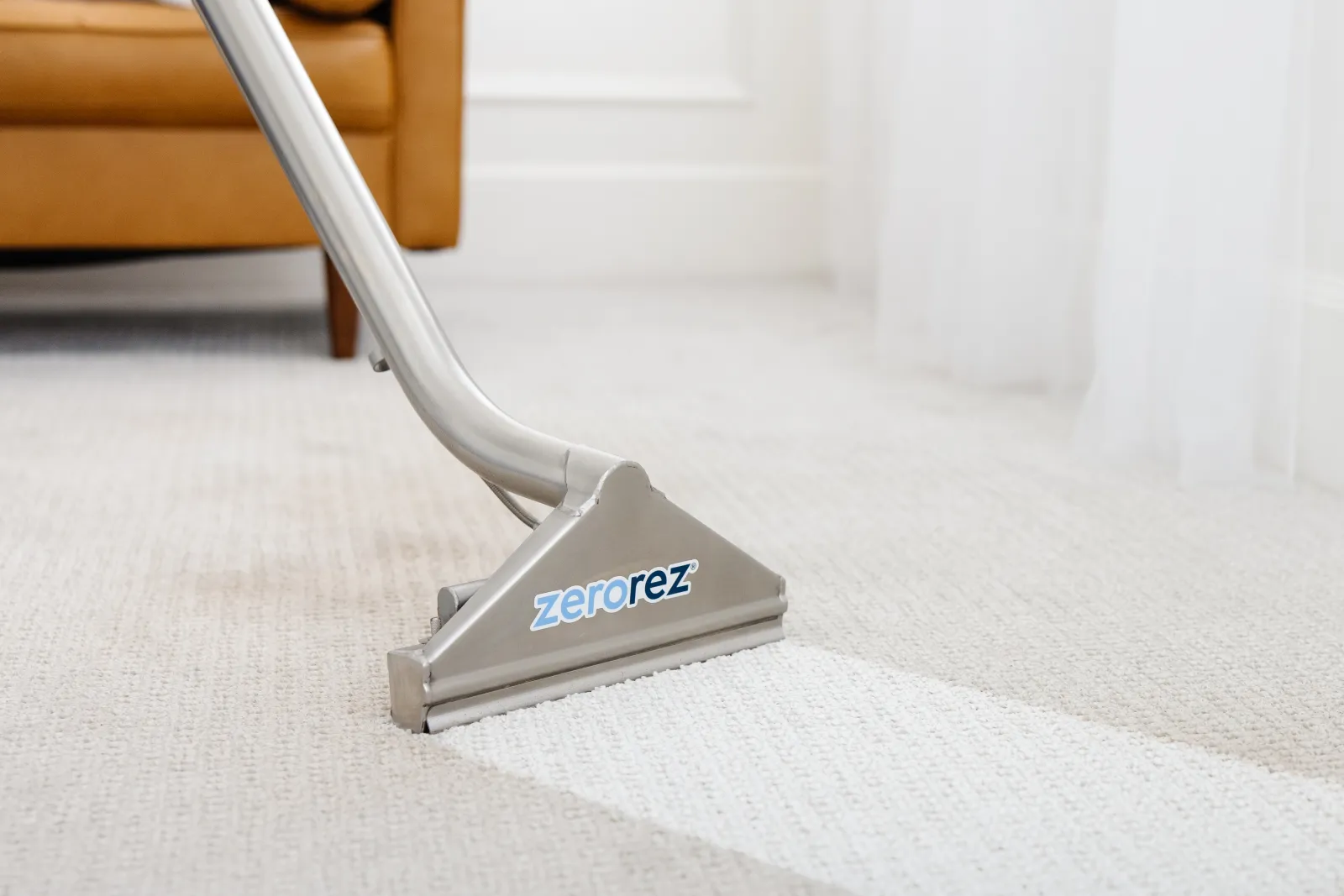 Close up of Zerorez Zr™ Wand cleaning a white carpet in a living room, leaving a clean stripe on the carpet where they've cleaned