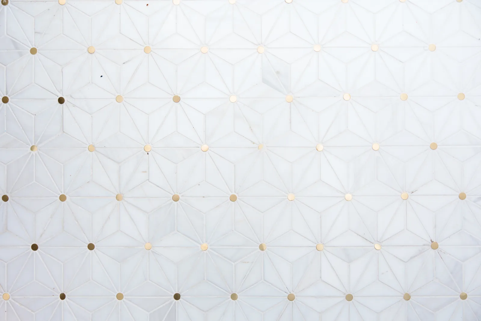 close up of a white tile geometric marble floor with gold circle tile inlaid