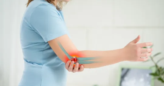 Person holding elbow with highlighted pain area and bone illustration indicating joint discomfort.