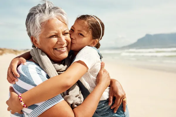 older woman hugging granddaughter on beach