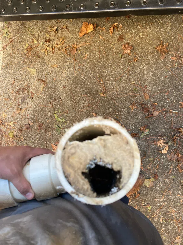 Cut section of the old kitchen drain pipe packed with compacted grease, with only a small opening left for water