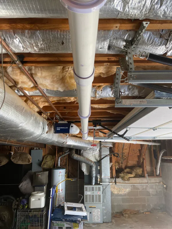 New PVC kitchen drain line installed overhead through the garage ceiling in a Marietta home, with primed and glued joints