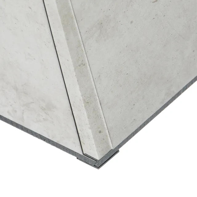 Close-up of a gray concrete corner joint with visible seams and textured surface on white background