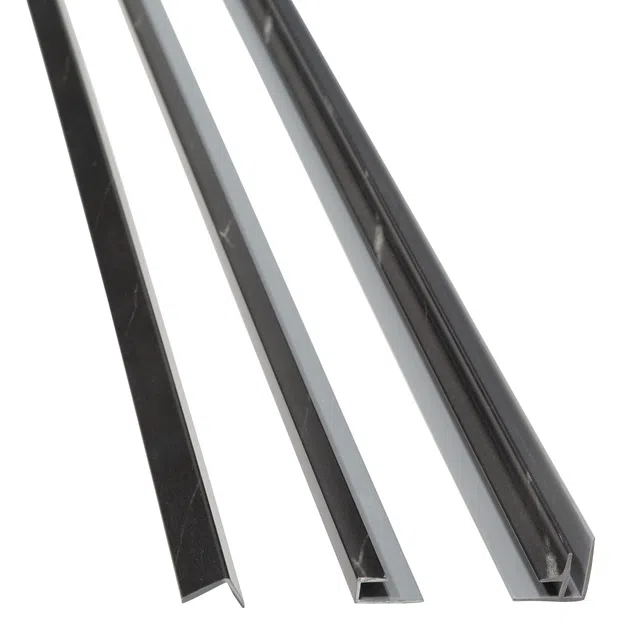 Close-up of three black and gray metal or plastic trim or edge strips of different shapes on white background.