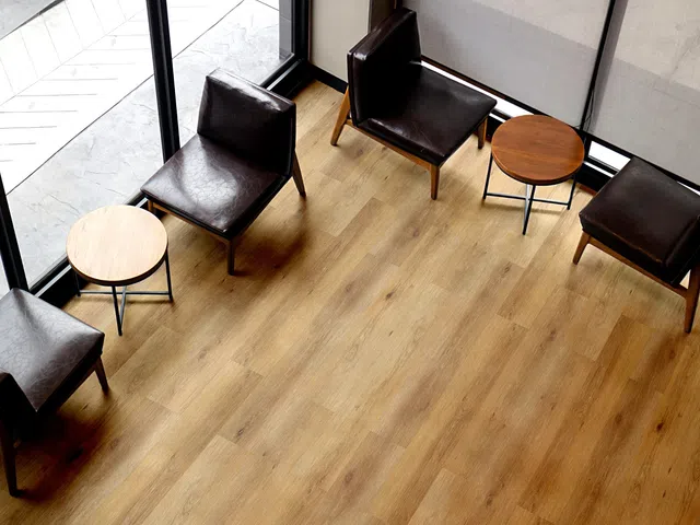 Top view of a modern seating area with four leather chairs and two round wooden tables on wood flooring
