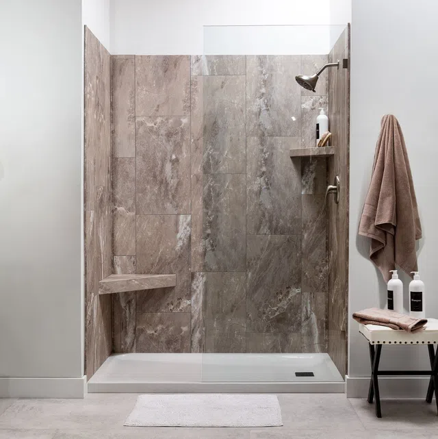 Modern walk-in shower with large stone tile walls, built-in bench, glass panel, and beige towel on hook