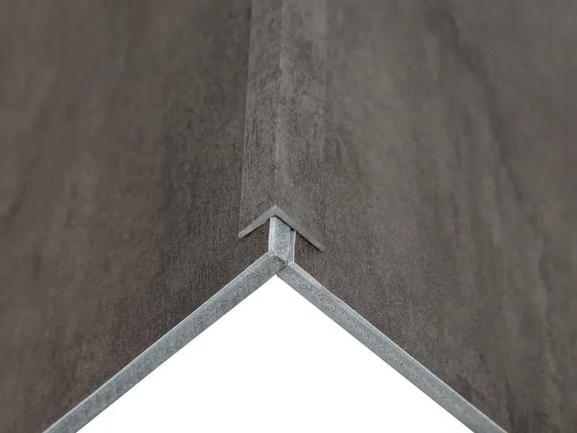Close-up of a corner joint with metal edging on textured gray panels against white background