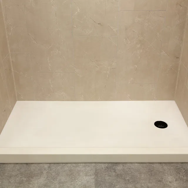 Modern beige tiled shower area with white rectangular shower base and black drain cover.