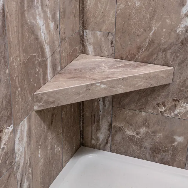 Corner marble shelf installed in a bathroom shower with brown veined tiles and white shower base.
