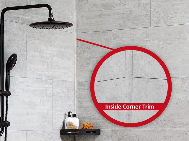 Modern shower with black rain showerhead and inside corner trim detail on gray tiled walls.