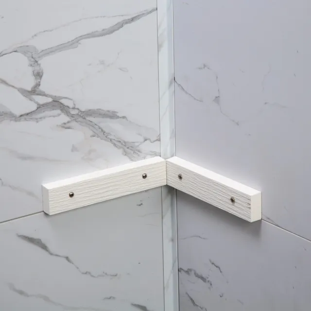 White marble tiled bathroom corner with two white wooden corner braces fixed with screws.