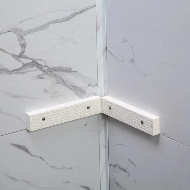 Corner of marble wall with white wooden brackets fixed by screws for structural support or decoration.