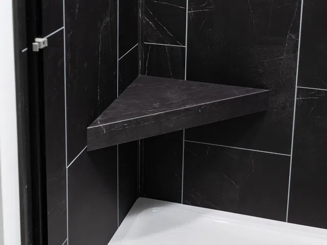 Modern corner shower seat made of black marble tiles in a sleek bathroom design.