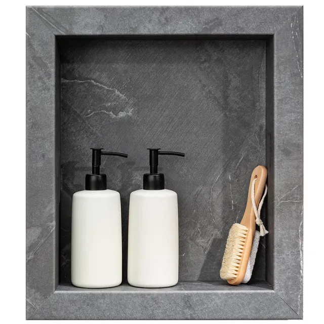 Two white pump bottles and a wooden brush with bristles inside a gray stone shower niche.
