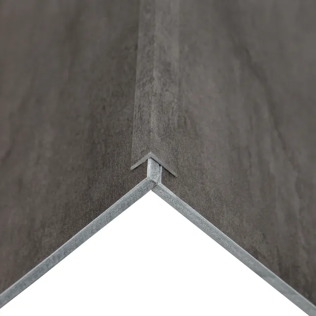 Close-up of a corner joint of two gray textured panels with metal edges forming a precise angle.