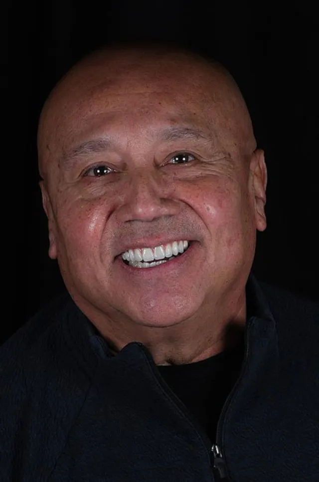 Smiling bald elderly man with a dark jacket against a black background