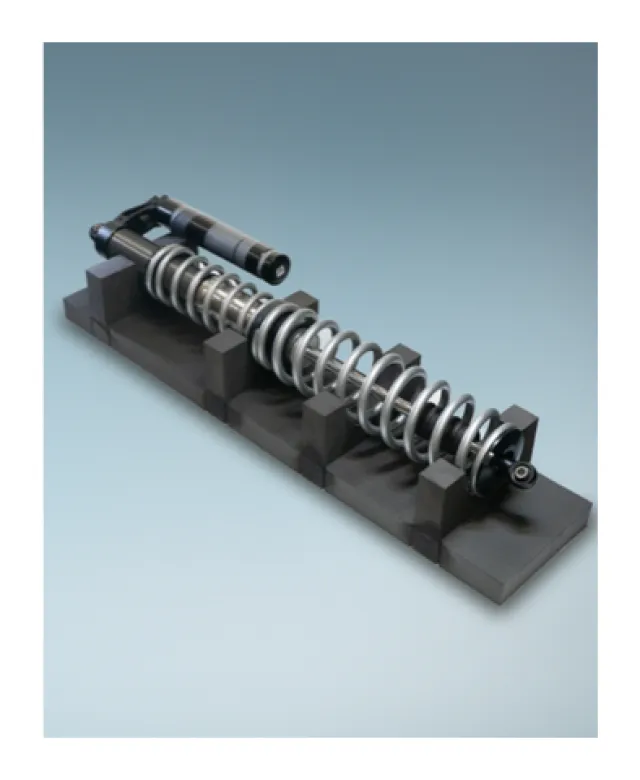 Close-up of a metallic shock absorber with coil spring mounted on a black stand against a gray background.