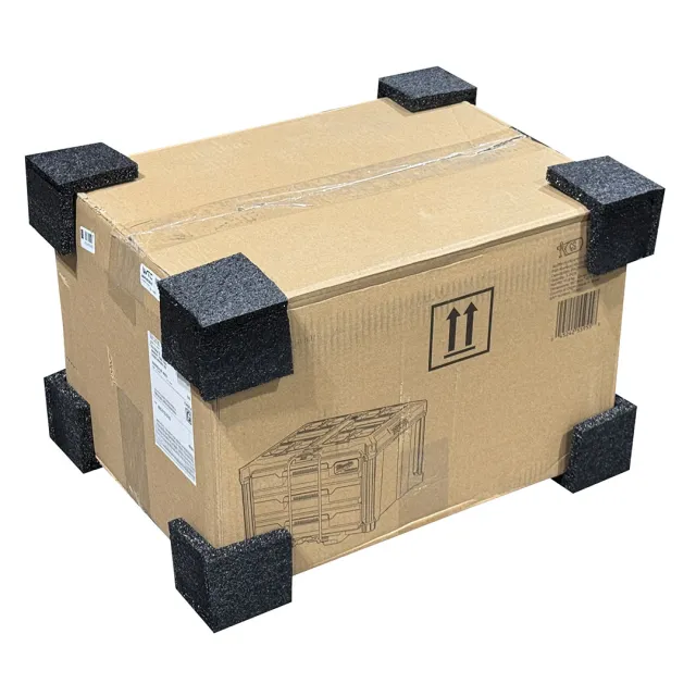 Cardboard shipping box secured with black foam corner protectors for impact protection during transit.