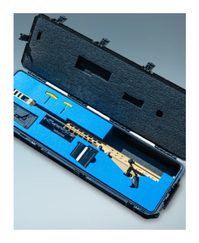 Open black protective case with blue foam inserts holding a tan training rifle and accessories