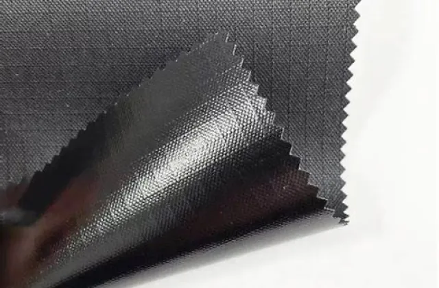 Close-up of black textured fabric with a glossy finish folded to show both sides and zigzag edges.