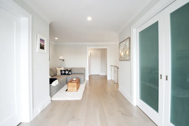 Bright modern living room with gray sofa, wood floor, white walls, star-patterned pillows, and sliding glass doors.