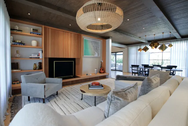 Spacious modern living room with gray sofa, wooden shelves, round coffee table, and large pendant lights.