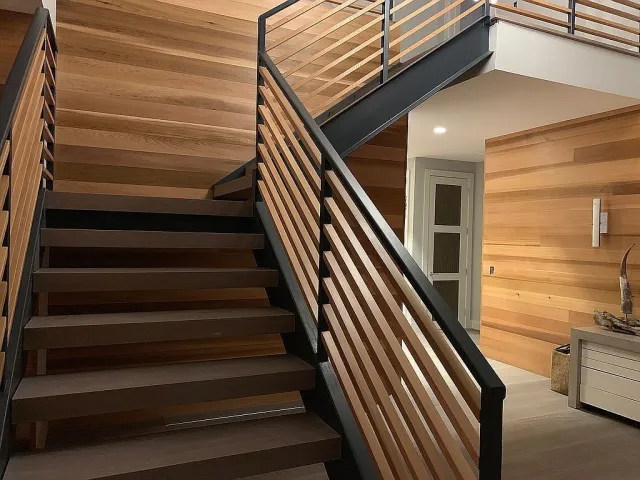 Modern interior with dark wood stairs and horizontal wood paneling on walls and railing accents