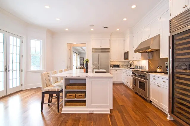 Bright modern kitchen with white cabinetry, large island, stainless steel appliances, and hardwood floors