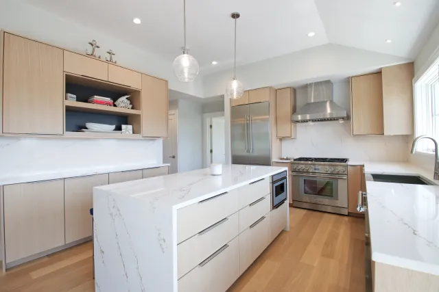 Modern kitchen with marble countertops, wooden cabinets, stainless steel appliances, and pendant lighting.