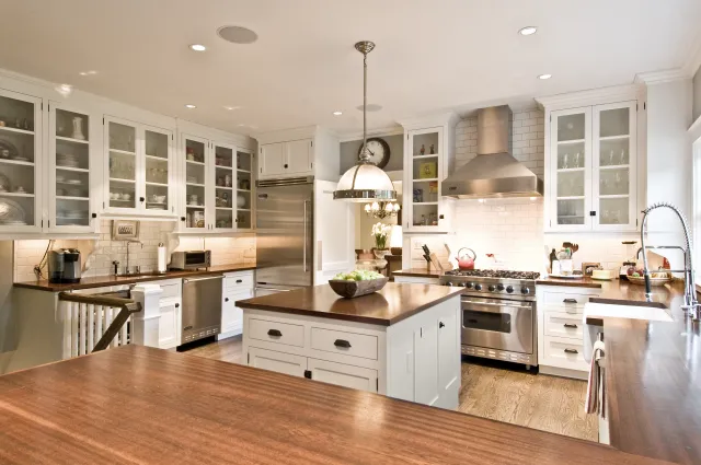 Bright modern kitchen with white cabinets, stainless steel appliances, center island, and wooden countertops.