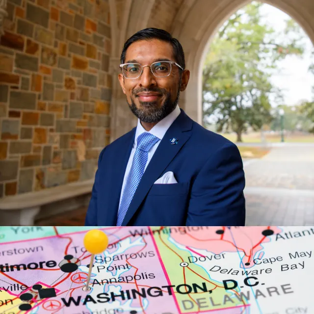 Professional man in navy suit smiling under stone archway with blurred outdoor park background
