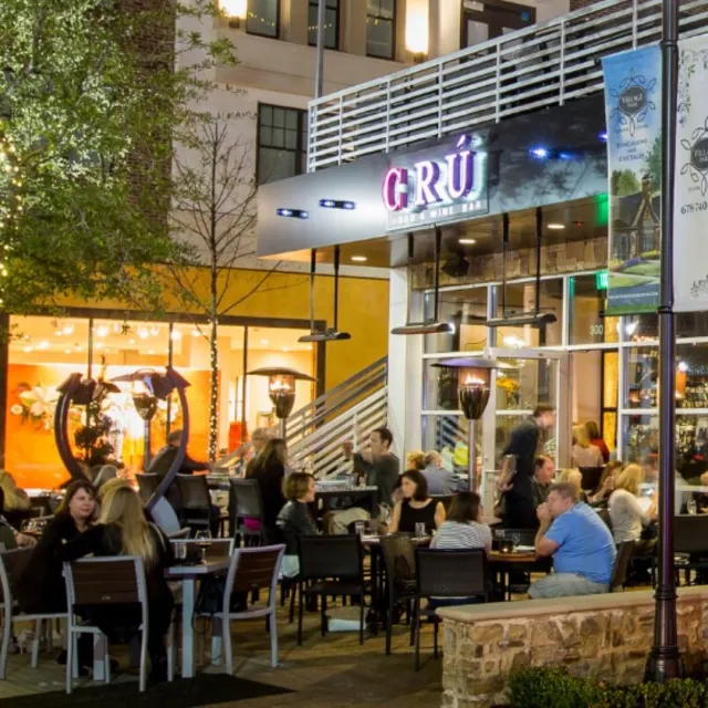Outdoor evening scene at G R Ü Wine Bar with diners and stylish ambiance.