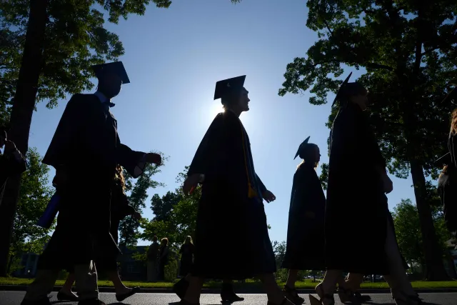 A group of alumni walk in front of the sunrise