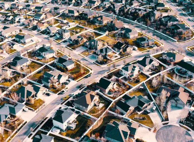 Aerial view of a suburban neighborhood with houses, roads, and cul-de-sacs on a sunny day.