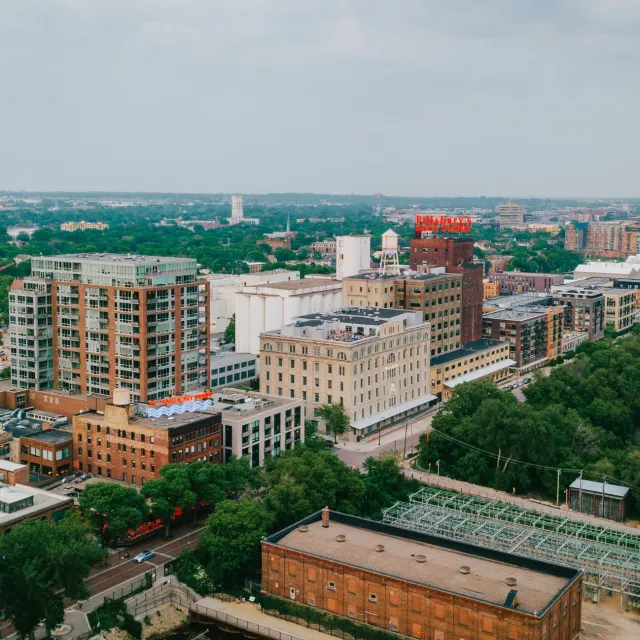 Aerial view of urban buildings and dense green trees under cloudy sky in a city landscape