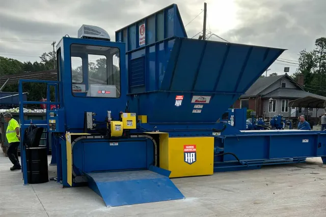 Large blue and yellow industrial machinery with Harris American logo on concrete surface outdoors.