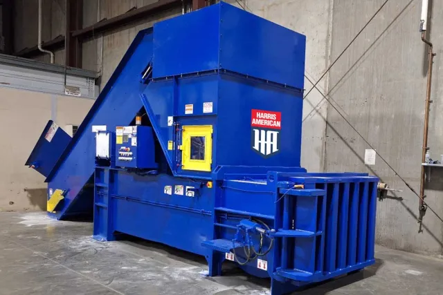 Large blue and yellow industrial machinery with Harris American logo on concrete surface outdoors.