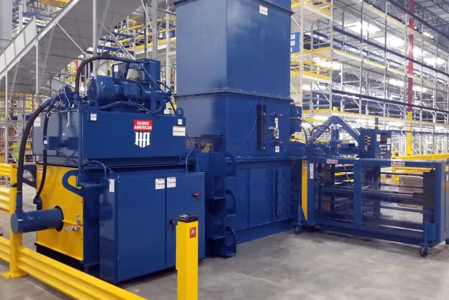 Large blue industrial machine with Harris American logo in a spacious warehouse with yellow safety barriers