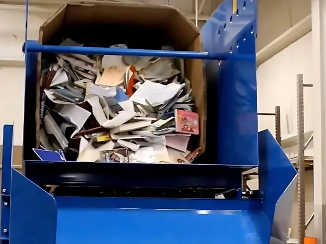 Blue industrial paper baler compresses mixed paper waste in a recycling facility.