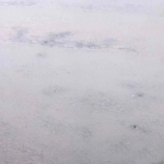 a white surface with a dark speckled surface