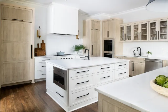 Modern kitchen with white island, wooden cabinets, hardwood floors, built-in appliances, and glass-front upper cabinets.
