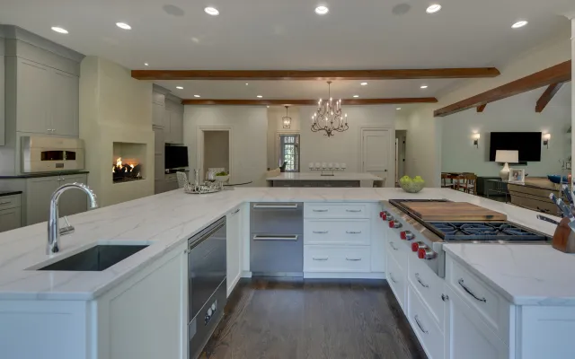 Modern kitchen with white marble countertops, stainless steel appliances, hardwood floors, and a built-in fireplace.