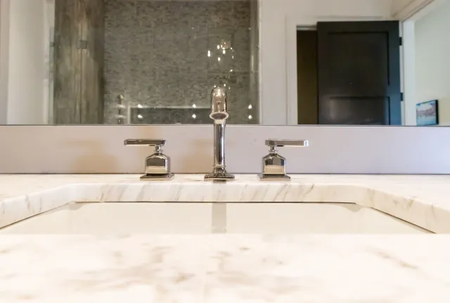 Close-up of a modern bathroom sink with chrome faucet and marble countertop in a bright setting